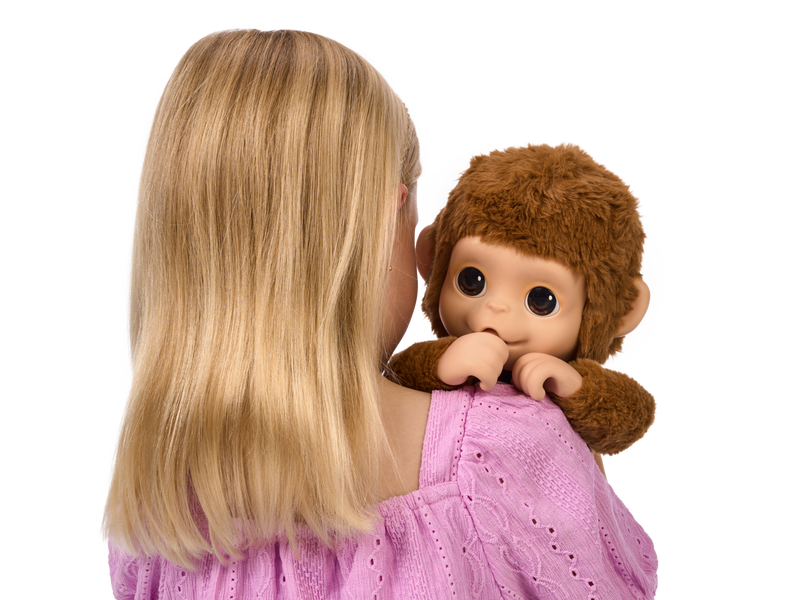 Girl hugging her Little Live Pets baby Monkey plush. 